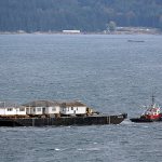 A tug towing a barge loaded with three houses anchors off Naval Magazine Indian Island in the south end of Port Townsend Bay on Tuesday evening. (Steve Mullensky/for Peninsula Daily News)