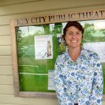 Margie McDonald stands in front of the student Wearable Art Show poster at the Key City Playhouse in Port Townsend where the show will take place Saturday afternoon. (Cydney McFarland/Peninsula Daily News).