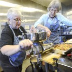 Cindy Birdsall, left, and Gwyn Wessel, mill cooked apples into applesauce as volunteers with the Washington State University Clallam County Extension Office turned 1,500 pounds of apples into applesauce Tuesday to be distributed in the county. (Jesse Major/Peninsula Daily News)