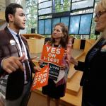 Dujie Tahat, left, hands out posters to Marilyn Balcerak, right, and Rep. Tana Senn, D-Mercer Island, center, before a Sept. 21 news conference in Bellevue promoting Initiative 1491, which will be on the ballot in the November elections. (Ted S. Warren/The Associated Press)
