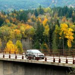 A vehicle makes its way over the Elwha River Bridge west of Port Angeles against a backdrop of trees in their full autumn colors. (Keith Thorpe/Peninsula Daily News)