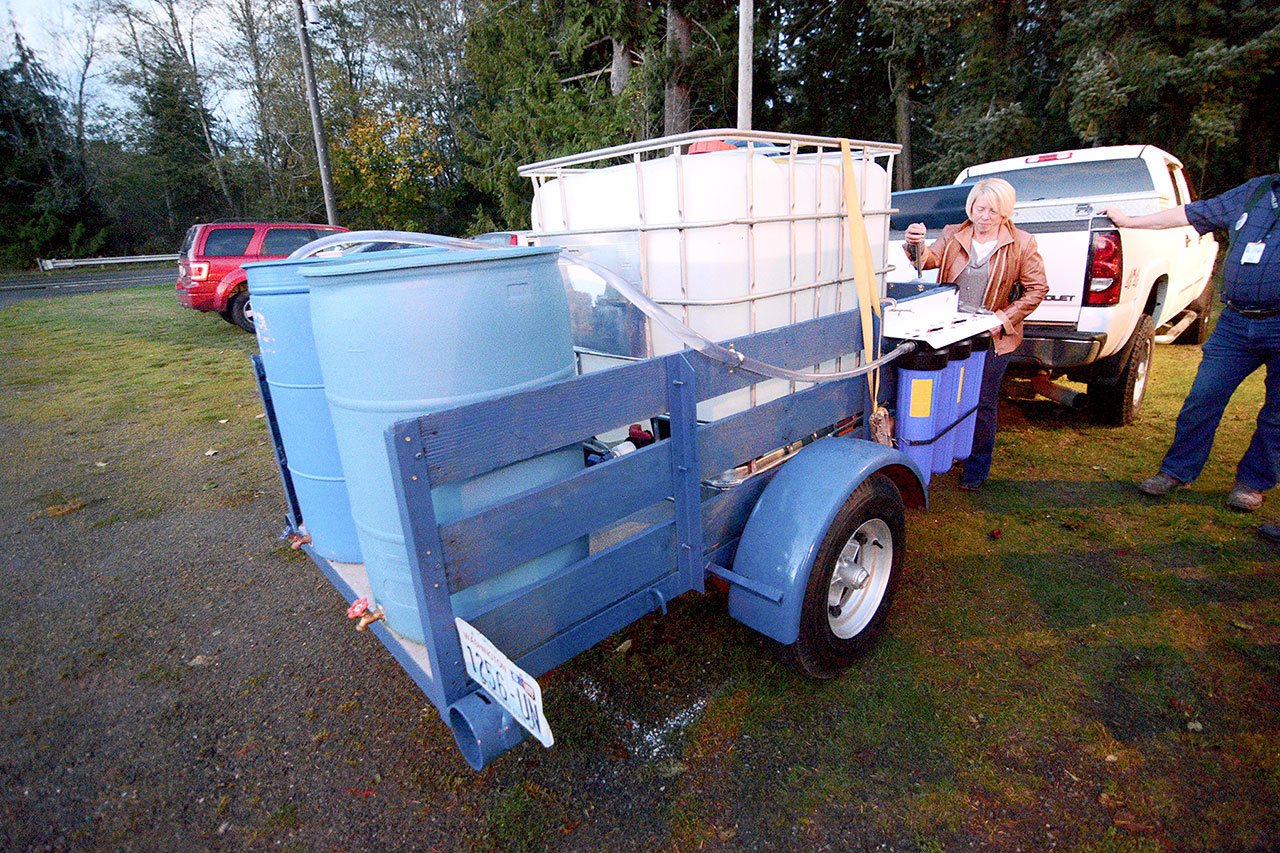 Connie Beauvais, Crescent Water Association manager, pulls a lever on the Joyce Emergency Planning and Preparation group&rsquo;s portable hand-powered water purification system Monday. (Jesse Major/Peninsula Daily News)