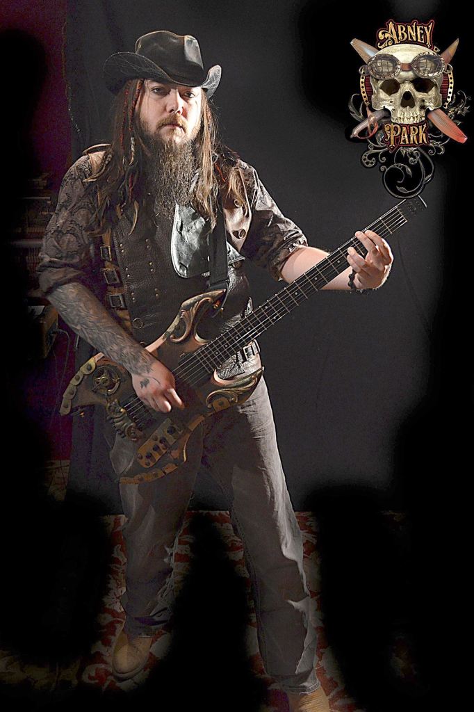 Abney park embodies steampunk, a subgenre of science fiction incorporating technology and aesthetic designs inspired by 19th-century industrial steam-powered machinery and the works of authors such as H. G. Wells and Jules Verne. Seen here is guitarist Josh Goering. &mdash; Abney Park.