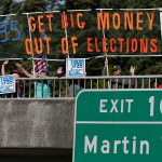 The Associated Press                                Supporters of Initiative 735 hold a banner above the Interstate 5 freeway during the evening commute in Lacey.