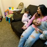 Danielle Mendoza helps two of her three children, Lola, 2 1/2, left, and Joseph, 5, get ready for bed in her apartment in Renton earlier this month. Mendoza, a cashier at a grocery store, is one of some 730,000 workers in Washington state who backers say would see their pay jump if voters approve Initiative 1433. (Ted S. Warren/The Associated Press)