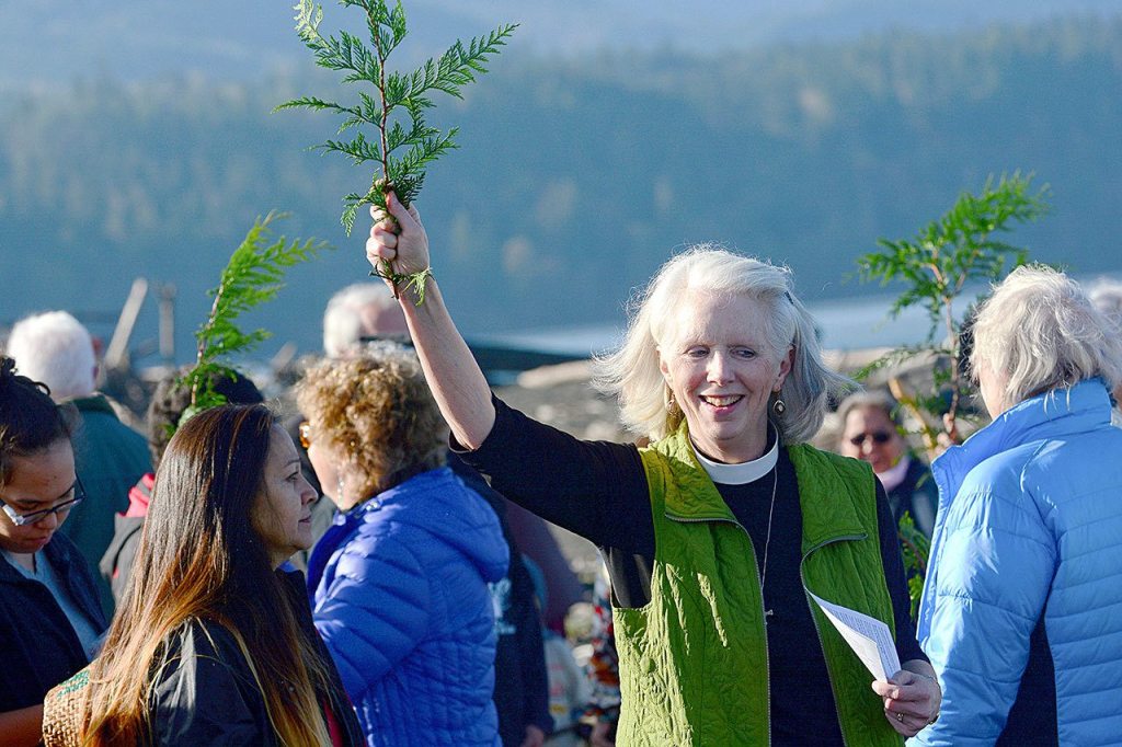 The Rev. Gail Wheatley of St. Andrew&rsquo;s Episcopal Church uses a cedar branch dipped in the mouth of the Elwha River to bless those who attended an event to show solidarity with the Standing Rock Sioux Tribe on Thursday. Wheatley organized the event. (Jesse Major/Peninsula Daily News)