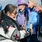 Sheryl Charging Whirlwind of the Lower Elwha Klallam Tribe prays as she uses sage and an eagle feather to smudge the 60-some people who gathered at the mouth of the Elwha River to show support for the Standing Rock Sioux Tribe on Thursday. (Jesse Major/Peninsula Daily News)