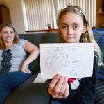 River Jensen, 10, holds up one of the cards she has made for the gift bags she is handing out to the homeless population. (Jesse Major/Peninsula Daily News)