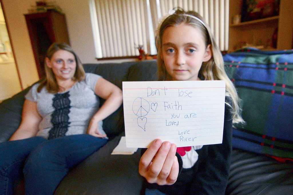 River Jensen, 10, holds up one of the cards she has made for the gift bags she is handing out to the homeless population. (Jesse Major/Peninsula Daily News)