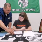 Keith Thorpe/Peninsula Daily News                                Port Angeles High School senior Lauren Lunt, seated, goes over paperwork with athletic director Dwayne Johnson prior to Lunt&rsquo;s signing of a letter of intent on Friday to attend University of Mary in Bismarck, N.D., on a softball scholarship. A portrait of her, her father, Jeff Lunt, and grandfather, Jim Lunt, was displayed on the table.