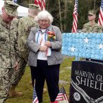 Joan Shields, the widow of Medal of Honor recipient Marvin Shields, stands beside his grave with a group of local servicemen who came out on Veterans Day to honor her late husband&rsquo;s service Friday. (Cydney McFarland/Peninsula Daily News)