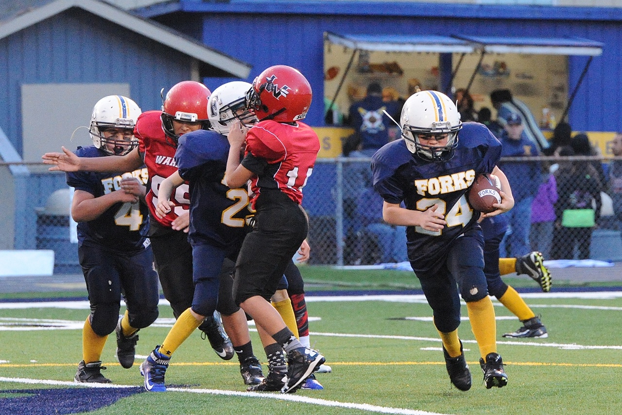 Lonnie Archibald/for Peninsula Daily News Forks A squad running back Nate Dahlgren (24) finds running room against Neah Bay during the West End Youth League Football Championships last Saturday. Forks defeated the Warriors 18-12 in triple overtime. Chimacum topped Neah Bay 33-20 in the B squad title game, while Forks knocked off Sequim 30-20 in the C squad championship.
