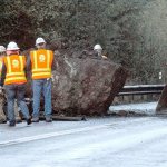State Department of Transportation workers prepare to push a refrigerator-sized boulder over the embankment over Lake Crescent on U.S. Highway 101 on Wednesday morning. (Keith Thorpe/Peninsula Daily News)