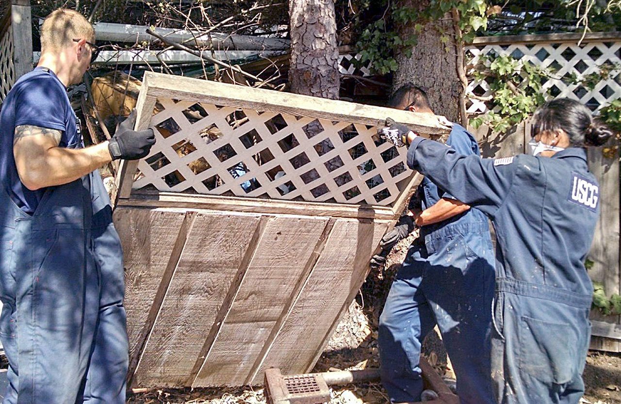 Three members of the U.S. Coast Guard help the Clallam County Hoarding Task Force clean up the home of an elderly person suffering from hoarding disorder earlier this year. (Clallam County Hoarding Task Force)