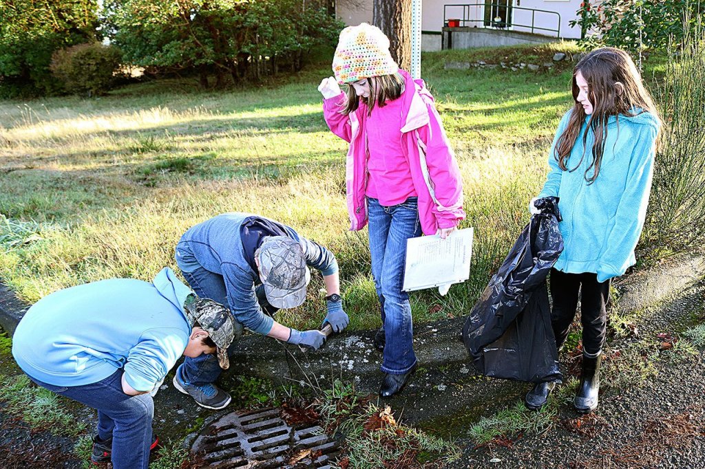 Applying plaques near storm drains in the Hamilton School area are, from left, Thomas Leonard, Peter Zelenka, Faith Carr and Gracie Underwood, fifth-grade students at Hamilton Elementary. (Port Angeles School District)