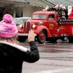 Emma Rhodes, age 6 of Sequim, stands on the corner of Sequim Ave and Washington St as Santa arrives in an old vintage Sequim fire engine on Saturday. Santa and the Irrigation Festival Court greeted all the people from the engine before they arrived at the Sequim plaza to greet children individually. (Dave Logan/for Peninsula Daily News)