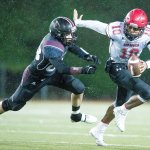 Neah Bay&rsquo;s Rwehabura Munyagi, right, avoids the pass rush of Lummi&rsquo;s Chance Poasa on Saturday, Nov. 26, at Everett Memorial Stadium in Everett.