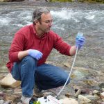 Michael K. Schwartz filters 5 liters of water to concentrate DNA on a filter to be analyzed at the National Genomics Center for Wildlife and Fish Conservation, on Rattlesnake Creek near Missoula, Mont., in 2014. (Kellie Carim/U.S. Forest Service via AP)