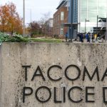 Flowers rest on a sign Thursday at Tacoma Police Department headquarters. (Ted S. Warren/The Associated Press)