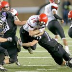 The Associated Press                                Neah Bay quarterback Cameron Buzzell (14) is tackled by Odessa-Harrington defensive linebacker John DeWulf (17) as he leaps for extra yardage in the first half of the Washington Div. 1B high school football championship Saturday at the Tacoma Dome.