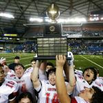 The Associated Press                                Neah Bay players, including quarterback Cameron Buzzell (14), celebrate with the trophy after they defeated Odessa-Harrington 64-34 in the Washington Div. 1B high school football championship on Saturday at the Tacoma Dome.