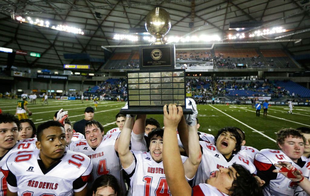 The Associated Press                                Neah Bay players, including quarterback Cameron Buzzell (14), celebrate with the trophy after they defeated Odessa-Harrington 64-34 in the Washington Div. 1B high school football championship on Saturday at the Tacoma Dome.