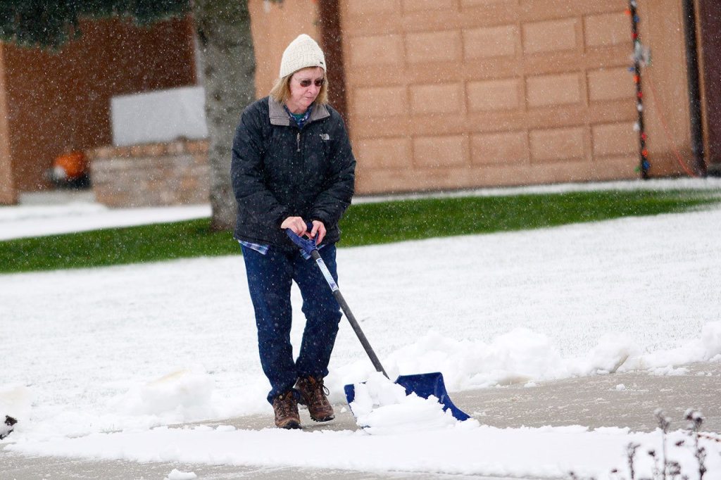 Marily Brown shovels snow from her driveway in Port Angeles on Monday morning. (Jesse Major/Peninsula Daily News)