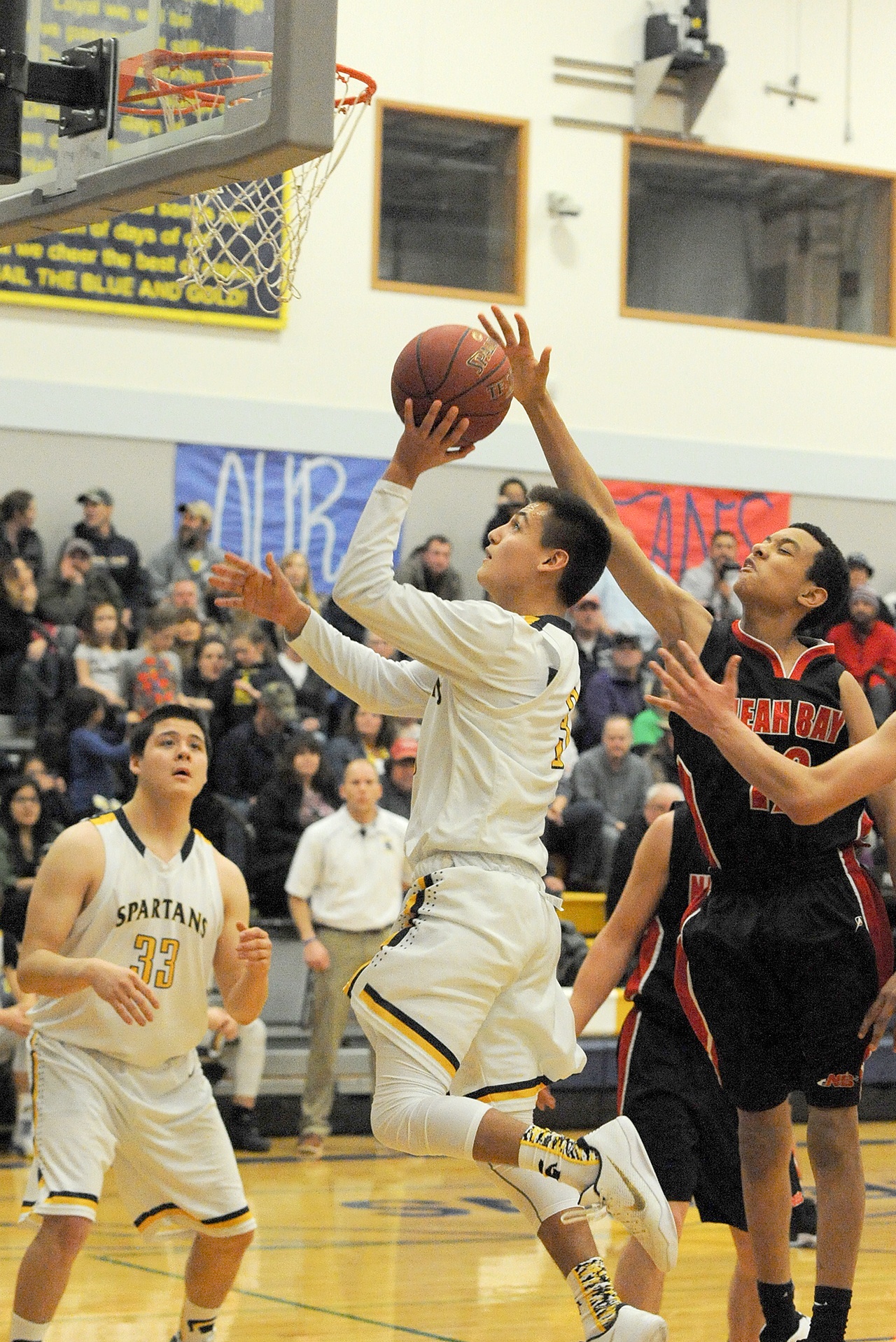 Lonnie Archibald/for Peninsula Daily News Forks&rsquo; Keishaun Ramsey shoots around the defense of Neah Bay&rsquo;s Sean Bitegeko while the Spartans&rsquo; Austin Flores looks on.