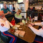 Marine Corps veterans Mark Schildknecht, front left, and Guy Iredale, right, chat with Smuggler&rsquo;s Landing owner Rick Mathis after the free meal he gave veterans last week. (Jesse Major/Peninsula Daily News)