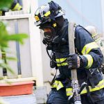Firefighter Steven Bentley of Clallam County Fire District No. 2 carries a hose after responding to a fire at 833 Cottonwood Lane east of Port Angeles on Tuesday afternoon. (Jesse Major/Peninsula Daily News)