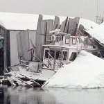 A boat lists under the weight of a collapsed boathouse at Port Angeles Boat Haven on Dec. 29, 1996. Heavy snow from a storm that began the day before, combined with the weight of rain, caved in numerous structures across the North Olympic Peninsula. (Keith Thorpe/Peninsula Daily News)