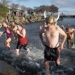 Chris Fowler of Port Angeles, wearing a viking hat, emerges from the chilly waters of Port Angeles Harbor with dozens of other people during the 2016 polar bear plunge in honor of the new year. (Keith Thorpe/Peninsula Daily News)