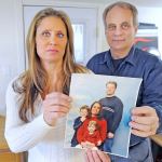 Joel Melom&rsquo;s ex-wife Dana Linderman and stepfather Tim McCray pose with a photo of Melom with his family while he was still married to Linderman in Sedro-Woolley. Melom&rsquo;s family is upset about a fake news story that was posted about the circumstances of his February 2016 death. (Scott Terrell/Skagit Valley Herald via AP)