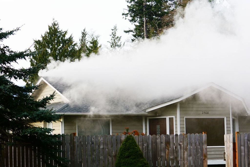 Smoke pours out of a house on the west side of Port Angeles that caught fire Sunday morning. (Jesse Major/Peninsula Daily News)