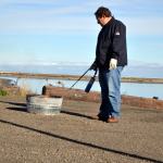 Scientist Robert Jeters, project manager for the Pacific Northwest National Laboratory&rsquo;s aggregator product, uses a propane burner to light an oil slick on fire during a recent demonstration. (Matthew Nash/Olympic Peninsula News Group)