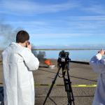 Staff with the Pacific Northwest National Laboratory watch an oil slick burn during a demonstration of how an aggregator wood product helps burn oil more efficiently in cold conditions. (Matthew Nash/Olympic Peninsula News Group)