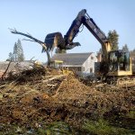 An excavator piles brush pulled from the banks of Peabody Creek near Ninth Street in Port Angeles on Wednesday to gain access to a broken water main beneath the creek bed. (Keith Thorpe/Peninsula Daily News)