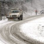 A snowplow clears slush from Mount Angeles Road near the Olympic National Park Visitor Center in Port Angeles as a vehicle sits in the ditch after sliding off the road Tuesday morning. (Keith Thorpe/Peninsula Daily News)