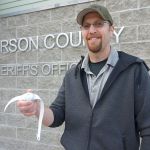 Jefferson County Sheriff&rsquo;s Office Detective Brett Anglin holds one of the devices used in Project LifeSaver to help law enforcement track people with cognitive disorders should they wander from their caregivers. (Cydney McFarland/Peninsula Daily News)