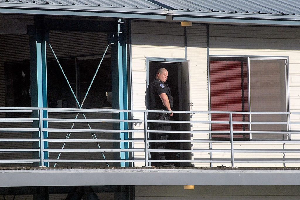 Port Angeles police Officer Mike Johnson stands watch at an office suite at Eighth and Vine streets where the suspect in a fatal shooting was arrested on Thursday. (Keith Thorpe/Peninsula Daily News)