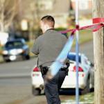 Detective Shane Martin of the Port Angeles Police Department puts police tape around 201 W. Ninth Street, where police say a man shot and killed his father. (Jesse Major / Peninsula Daily News)