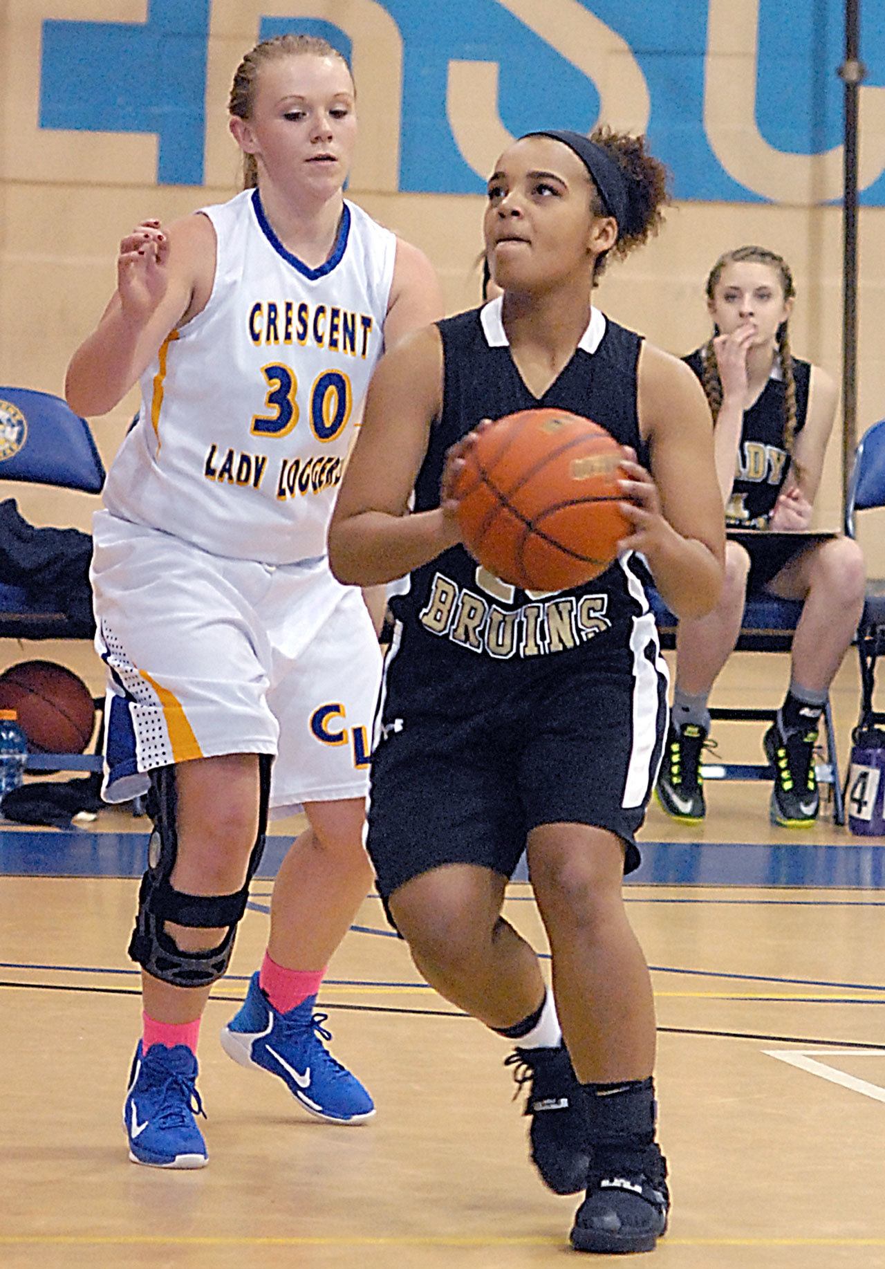 Keith Thorpe/Peninsula Daily News Clallam Bay&rsquo;s Atokena Abe, right, drives to the lane past Crescent&rsquo;s Alyssa Hutto in the fourth quarter on Friday night in Joyce.