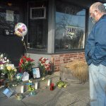 Pete Rennie of Port Angeles, a former patron of Van Goes Gourmet Pizza & Mexican, pays his respects at a make-shift shrine to restaurant-owner Clint Darrow at the front door of the Port Angeles business on Saturday. (Keith Thorpe/Peninsula Daily News)