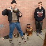 Devin Jensen and his mentor through the YMCA, Francesco Tortorici, hold a demonstration on stoves at Blue Heron Middle School. (Cydney McFarland/Peninsula Daily News)