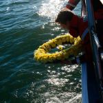 Boatswain&rsquo;s Mate Third Class Austin Kettleson, from Coast Guard Station Cape Disappointment, places a memorial wreath into the Pacific Ocean near the North Head Light in Ilwaco during a memorial ceremony Saturday. (Kaitlin Florez/U.S. Coast Guard)