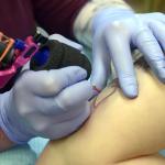 Mount Vernon tattoo artist Darius Sessions creates a tattoo Dec 30 on Rachel Olson at Session&rsquo;s business, Good Vibes Body Art in Mount Vernon. The tattoo honors Olson&rsquo;s mother and her successful battle with breast cancer. (Scott Terrell/Skagit Valley Herald via AP)