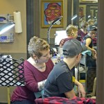 Mount Vernon tattoo artist Darius Sessions creates a tattoo Dec 30 on Rachel Olson at Session&rsquo;s business, Good Vibes Body Art in Mount Vernon. The tattoo honors Olson&rsquo;s mother and her successful battle with breast cancer. (Scott Terrell/Skagit Valley Herald via AP)