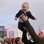 A man lifts a baby above the crowd before a women&rsquo;s march Saturday in Seattle. (Elaine Thompson/The Associated Press)