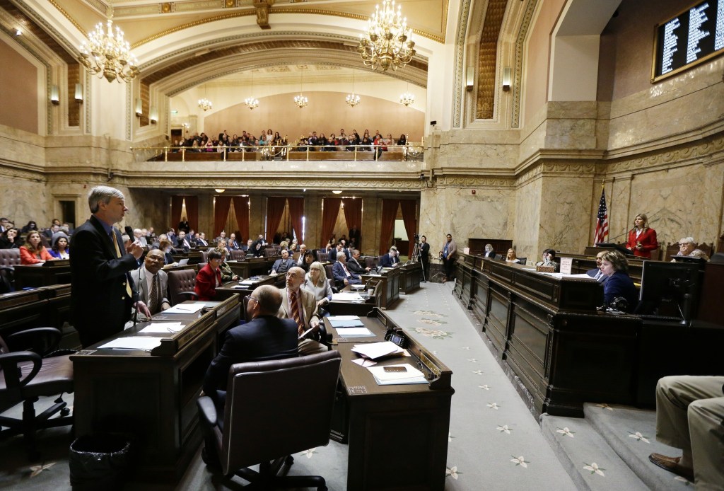Rep. Pat Sullivan, D-Covington, left, speaks on the state House floor on Monday at the Capitol in Olympia. (Ted S. Warren/The Associated Press)