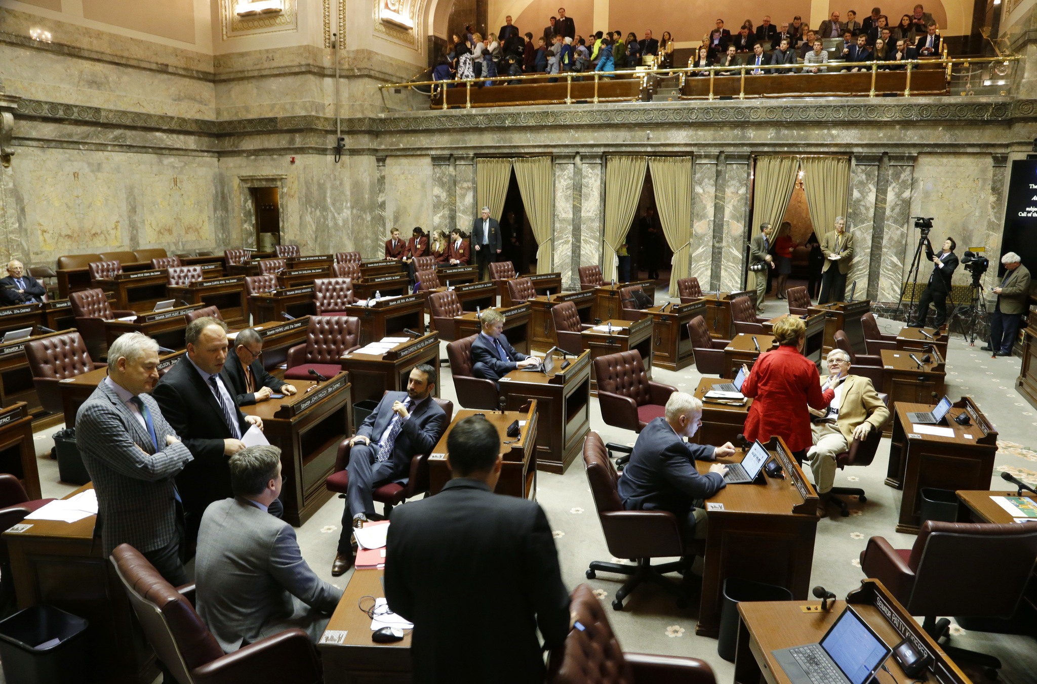 Democrats confer on the Senate floor as the Republican side sits empty during a recess Friday in Olympia. Senators were debating whether to vote on the &ldquo;levy cliff&rdquo; bill, which would delay a reduction in the amount of money school districts can collect though property taxes. (Ted S. Warren/The Associated Press)